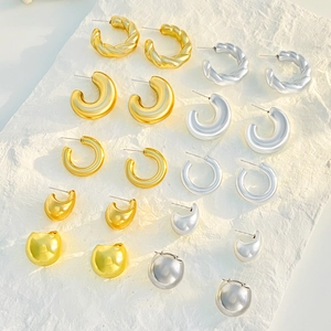 Detailed macro view of assorted gold and silver polished water drop and hoop earrings