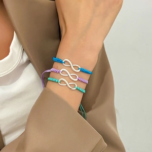 Close-up of three colorful woven infinity charm bracelets on a model's wrist
