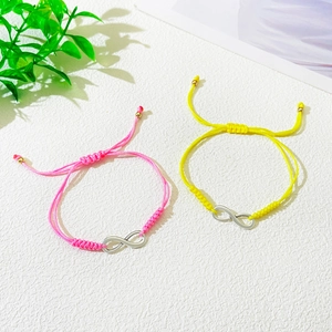 Close-up of pink and yellow adjustable infinity symbol friendship braided bracelets