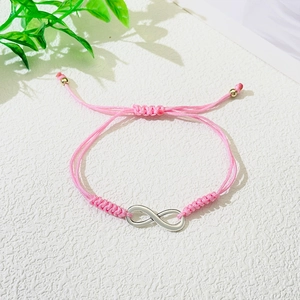 Close-up of pink braided cord infinity bracelet with adjustable gold beads and silver charm