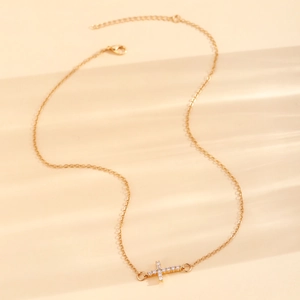 Detail einer zweilagigen Goldkette mit horizontalem Kreuzanhänger und Karabinerverschluss