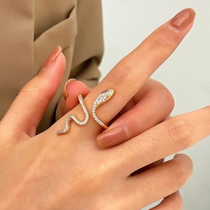 Detailed close-up of a gold snake wrap ring with shimmering white cubic zirconia on a finger