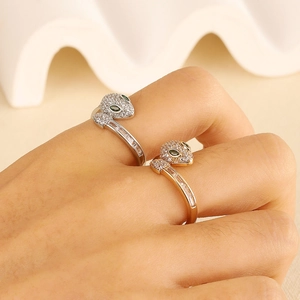 Close-up of gold and silver leopard rings with micro-paved crystals and green emerald eyes