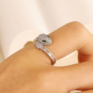 Macro shot of silver snake ring with green stone eyes and shimmering zircon micro-pave stones