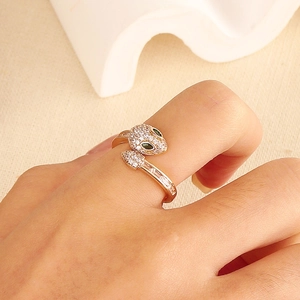 Macro detail of gold snake ring with micro-pave zircons and green gemstone eyes