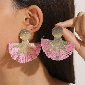 Macro di orecchini oversize con frange di seta rosa e dettagli dorati scintillanti