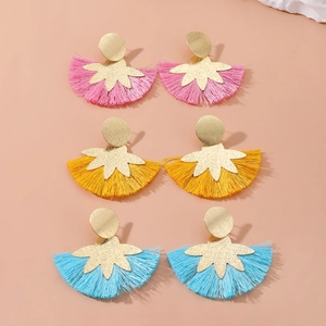 Dettaglio dei colorati orecchini con nappe di seta in rosa, giallo e blu