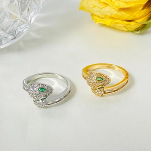 Detailed close-up of snake head rings with zircon micro-paving and green gemstone eyes