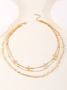 Detail einer drelagigen Goldkette mit Kreuzanhängern und Perlen auf weißem Hintergrund
