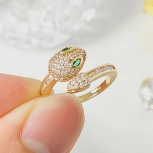 Detail of gold snake ring featuring green gem eyes and sparkling white pavé zircons