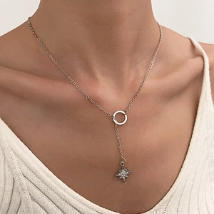 Close-up of a silver Y-necklace with a sparkling star pendant worn by a model