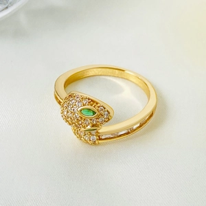 Detail of gold snake ring with micro-paved white zircons and emerald green stone eye