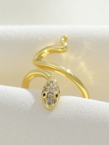 Macro view of gold snake ring with zircon inlay on luxury ivory silk background