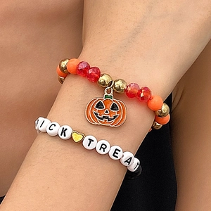 Detalle de pulseras de Halloween con dije de calabaza y letras de TRICK OR TREAT