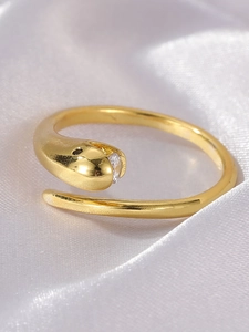 Macro view of gold snake ring with zircon stone on white silk background