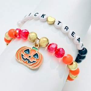 Detalle macro del set de pulseras de Halloween con letras Trick Treat y colgante de calabaza
