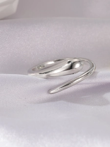 Macro shot of silver snake-shaped ring with black zircon eye on purple silk background