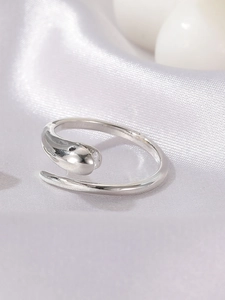Macro shot of silver snake-shaped open ring with mirror polish on grey silk background