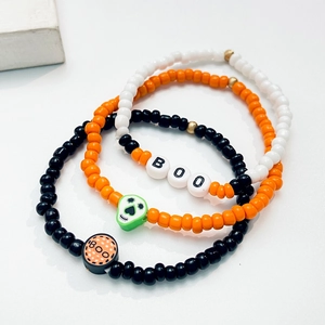 Detalle de pulseras de Halloween con letras BOO, cuentas de calavera y patrones festivos