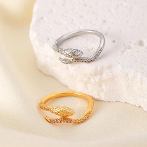 Macro shot of gold and silver snake rings with cubic zirconia on silk and stone