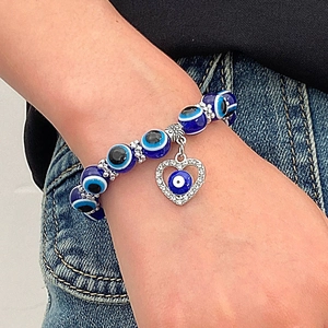 Detalle de pulsera de cuentas Evil Eye azul con colgante de corazón y cristales en la muñeca