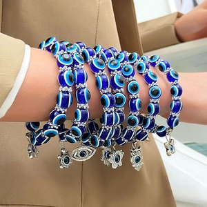 Detalle de pulseras de cuentas de ojo azul con colgantes de animales plateados en la muñeca