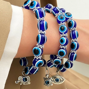 Detalle macro de pulsera Evil Eye con cuentas azules y dijes de elefante y tortuga de plata