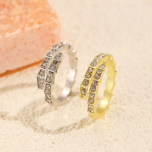 Macro shot of gold and silver snake rings with cubic zirconia on a warm stone background