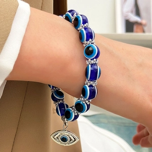 Primer plano de una pulsera de cuentas de ojo turco azul con un colgante de pestaña plateado