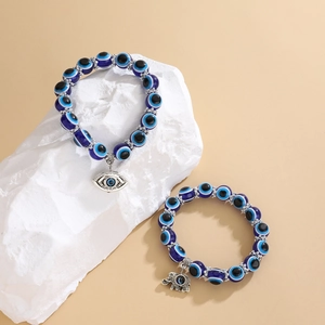 Primer plano de cuentas de resina Evil Eye azul y colgantes sobre piedra blanca