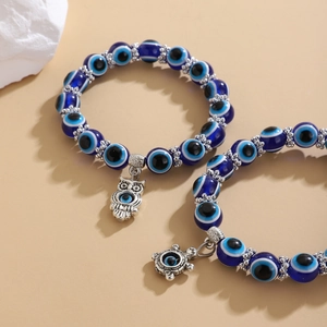 Detalle de pulseras de cuentas de ojo turco con colgantes de búho y tortuga plateados