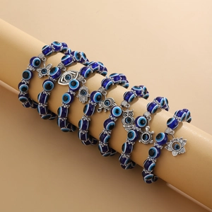 Pulseras de cuentas Evil Eye azules con varios dijes plateados en un soporte de exhibición