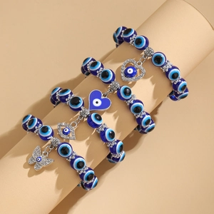 Detalle del conjunto de pulseras de cuentas azules con dijes de corazón, ojo y mariposa