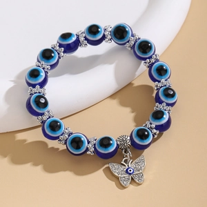Detalle de pulsera de cuentas de ojo turco con colgante de mariposa brillante y piezas plata
