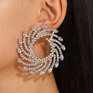 Detailaufnahme großer Spiral-Ohrringe mit glitzernden Kristallen am Modelohr