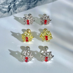 Macro detail of spiderweb zircon ear studs in silver and gold with red crystals