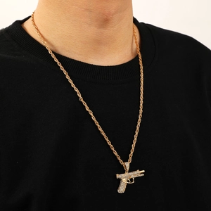 Macro shot of hip-hop gold rope chain and iced-out handgun pendant with clear rhinestones