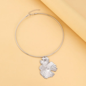 Close-up of silver metal choker with large textured fan pendant and lobster clasp detail