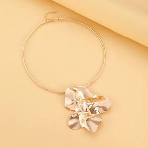 Macro shot of gold collar necklace with large irregular metal flower pendant detail