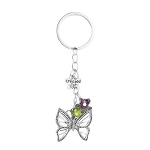 Macro shot of silver butterfly keychain with engraved floral tag and colored beads