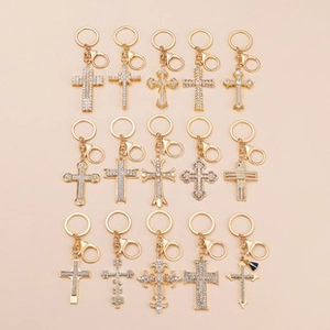 Detail showing 15 varieties of golden cross keychains with rhinestones and lobster clasps