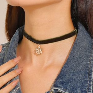 Detail of dark green velvet choker featuring a golden snowflake pendant with crystals