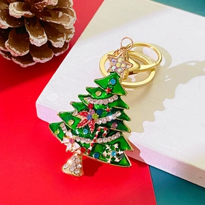 Detail of Christmas tree keychain with green enamel and rhinestones on festive background