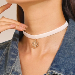 Detail of white velvet choker featuring a golden snowflake pendant with sparkling rhinestones