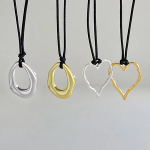 Unregelmäßige Herz- und Geometrie-Anhänger in Silber und Gold mit schwarzer Kordel