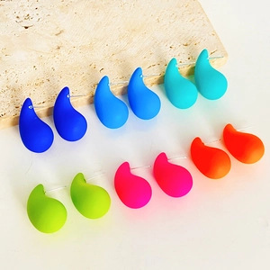 Minimalist matte teardrop stud earrings in six vibrant colors on stone background