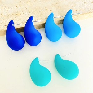 Detailed view of matte waterdrop earrings in navy, sky, and teal blue tones set on stone