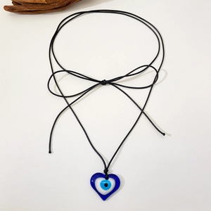 Detailansicht eines blauen Evil Eye Herzanhängers an schwarzer Schnur als Schleife