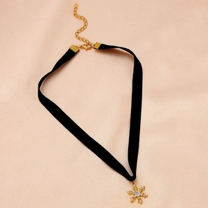 Close-up of black velvet choker with a gold snowflake pendant and sparkling rhinestones