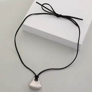 Détail d'un pendentif trapèze argenté minimaliste sur un collier en cordon noir stylé
